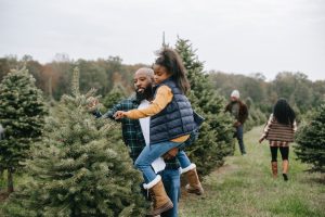 father and daughter look at Christmas trees and they are wearing vests