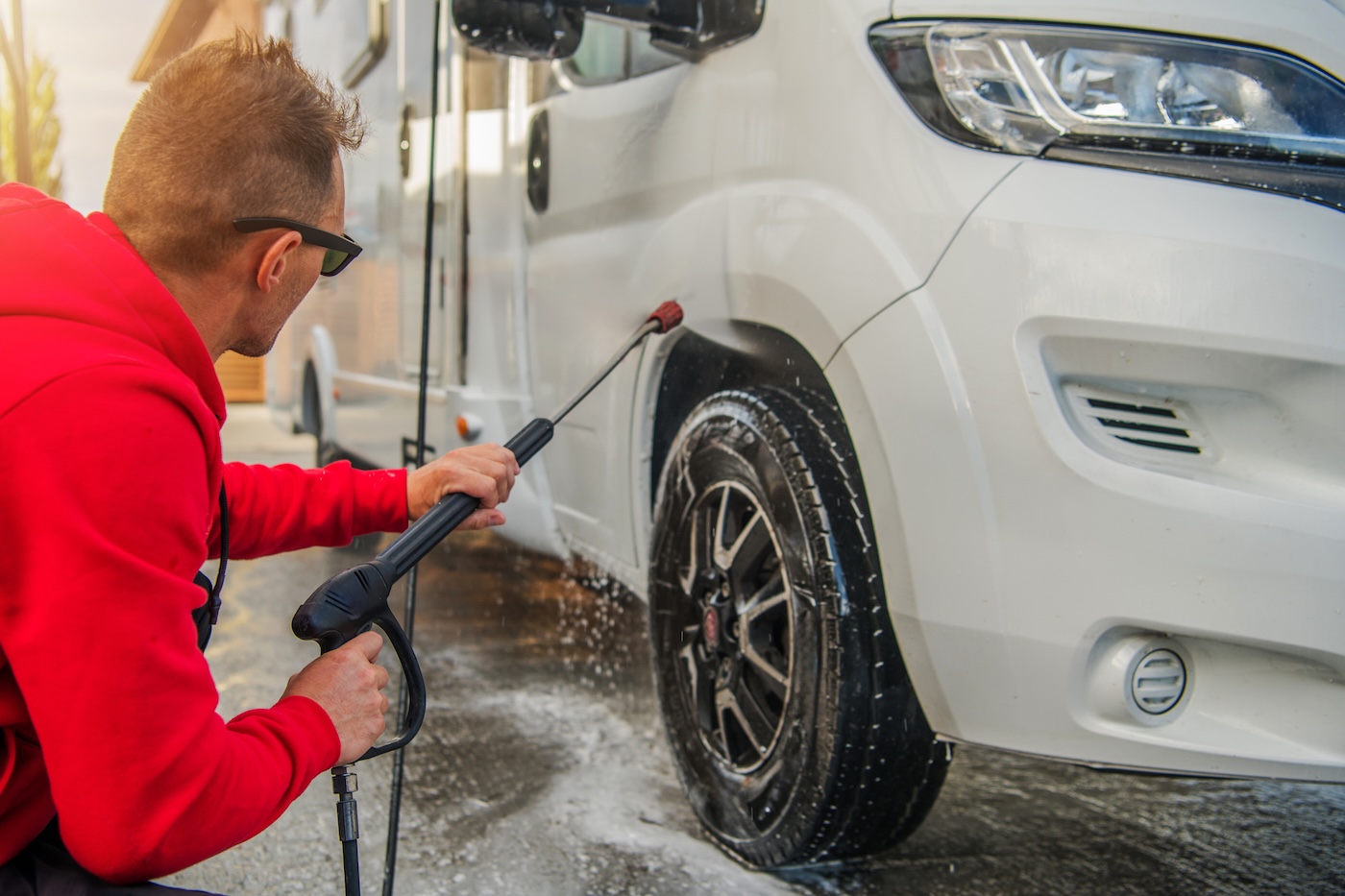 A person washing a motorhome wheel