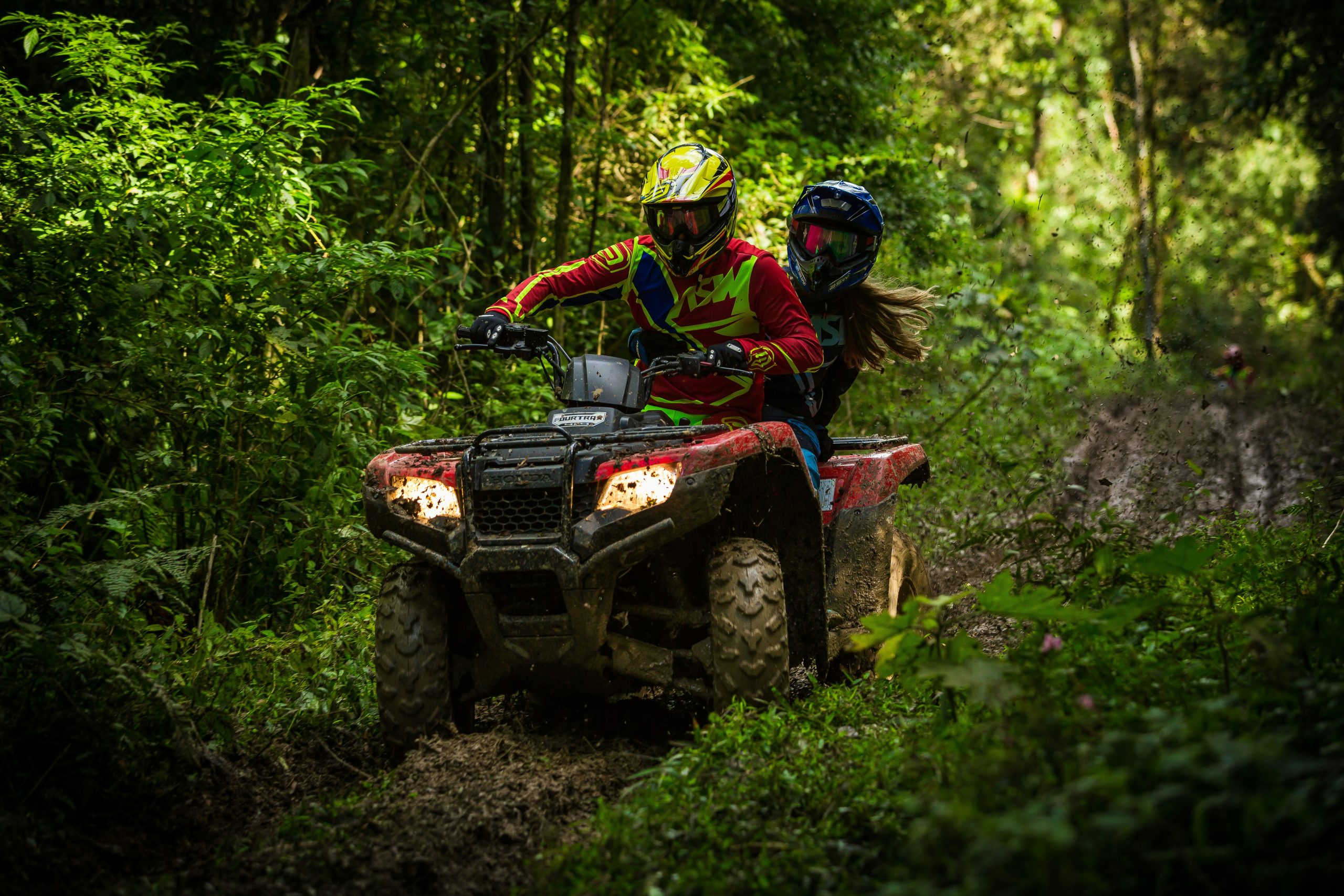 A rider driving an ATV along a wooded trail