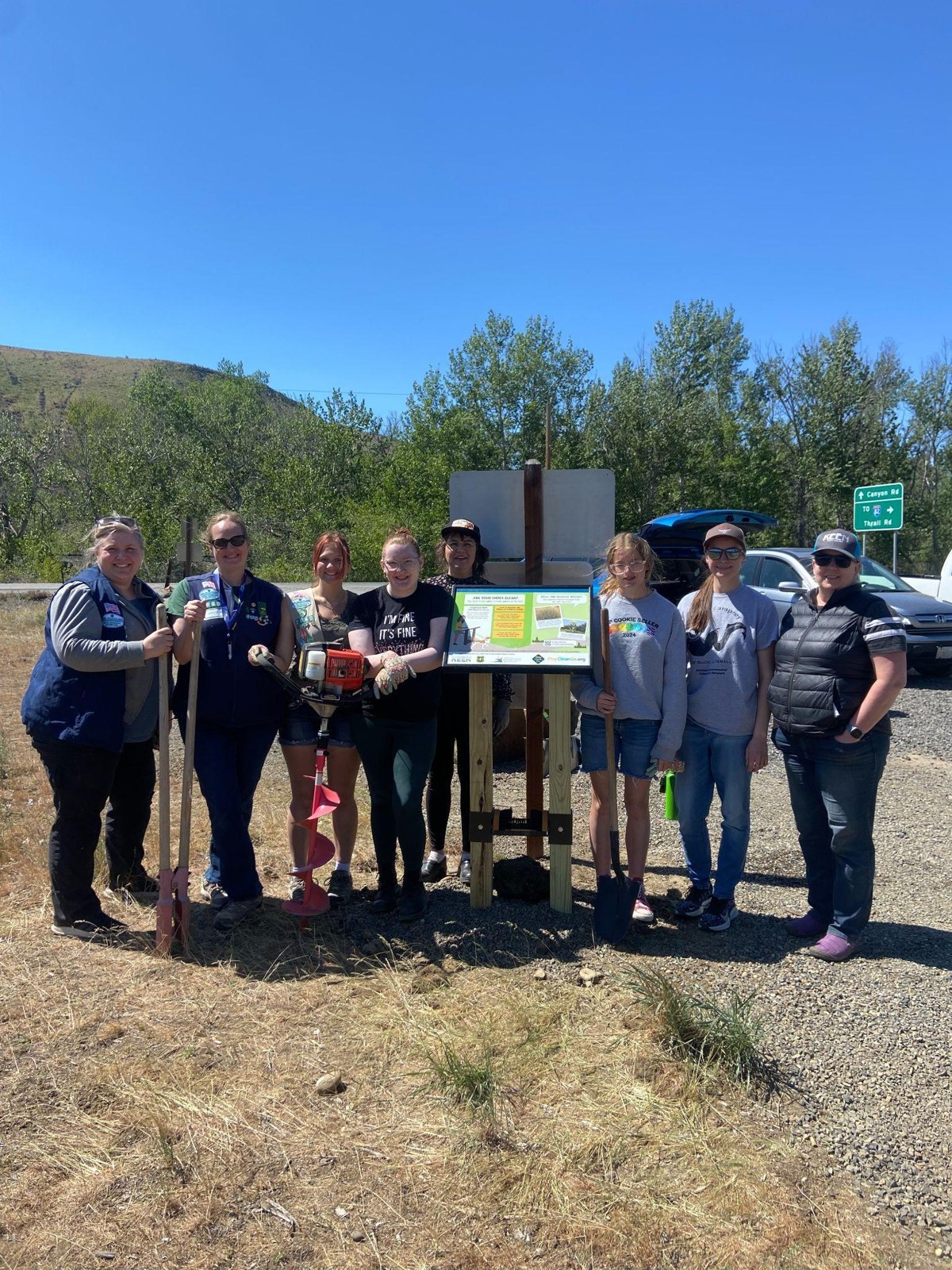 Community members gathered around a trailhead prevention station